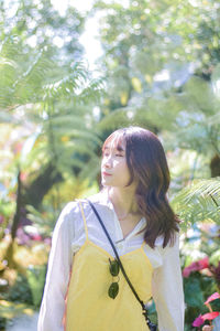 Young woman standing against plants