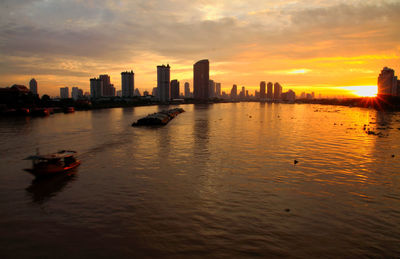 Scenic view of sea and buildings against sky during sunset