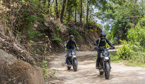 Two friends riding their scrambler motorcycles through forrest