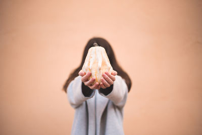 Midsection of woman holding apple against wall