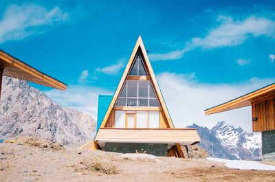 House on snowcapped mountain against sky