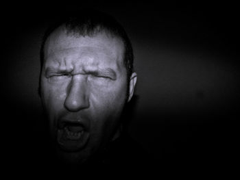 Close-up of angry blind man against black background