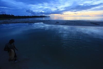 Woman on sea shore against sky during sunset