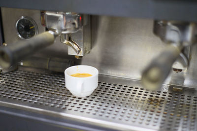 Close-up of coffee cup and espresso maker in kitchen