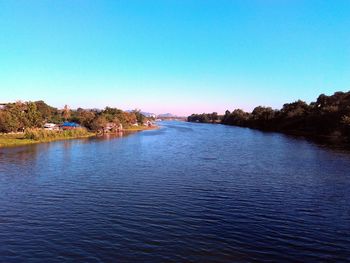 Scenic view of calm river against blue sky