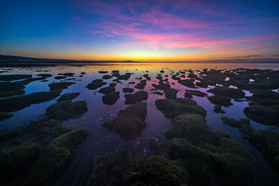 Rocks on beach against sky during sunset