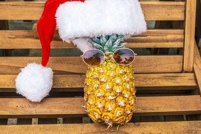 Portrait of relaxing funny pineapplewearing sunglasses and santa claus hat lies on sun lounger 