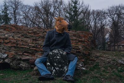 Man wearing horse mask while holding mirror