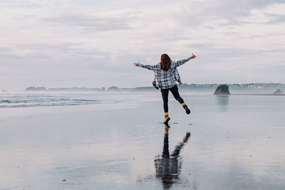 Full length of woman standing at beach against sky