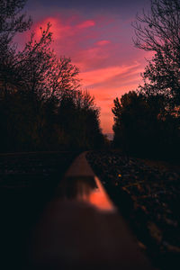 Surface level of railroad tracks against sky during sunset