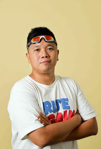 Portrait of man wearing sunglasses standing against wall