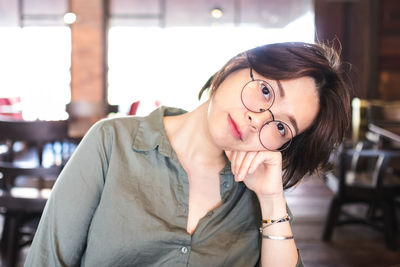 Portrait of young woman with eyeglasses on table