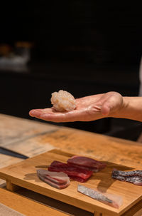 Chef serving scallop nigiri sushi on hand