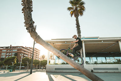 Low angle view of man with bicycle performing stunt against clear sky