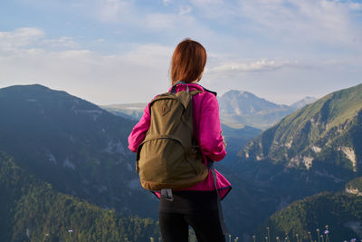 Rear view of woman looking at mountains against sky