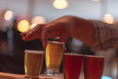 Midsection of woman holding beer glass on table