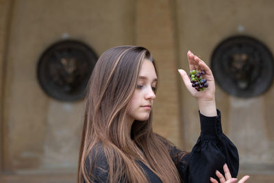 Young woman holding berries standing against historical building