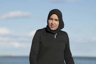 Portrait of young woman standing against sea