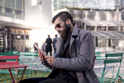 Young hipster businessman consults his laptop in the heart of city