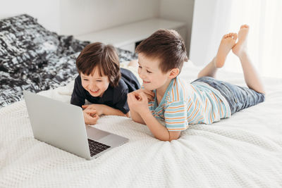 Distance learning at home. boy schoolboy sits on bed and watches webinar on digital tablet laptop.