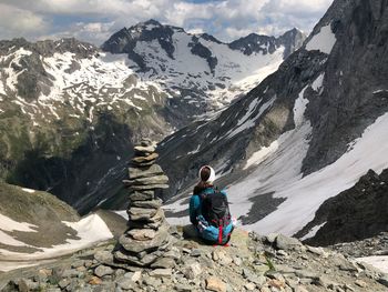 Rear view of man sitting on rocks against mountains