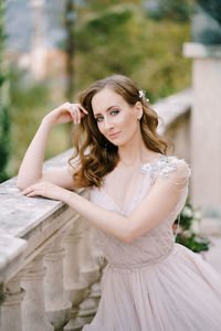 Portrait of young woman standing by railing