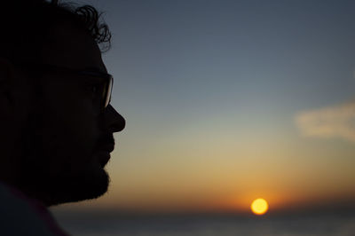 Close-up portrait of young man against sky during sunset