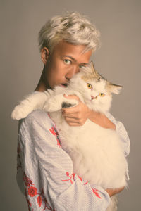 Portrait of woman with cat against gray background