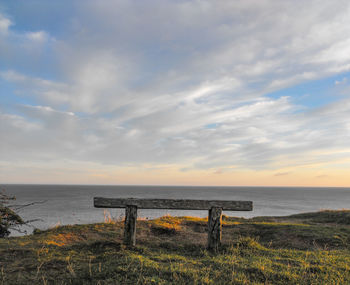 Scenic view of bench by sea against sky