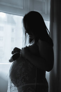 Pregnant woman with shoes standing at home