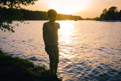 Full length of man standing on beach against sky during sunset