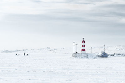 Lighthouse by sea against sky during winter