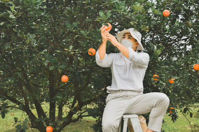 Full length of man holding orange tree