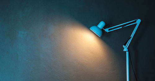 Illuminated desk lamp against wall