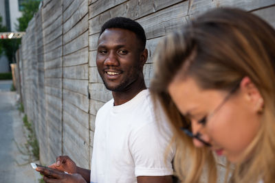 Smiling man looking at friends while standing outdoors