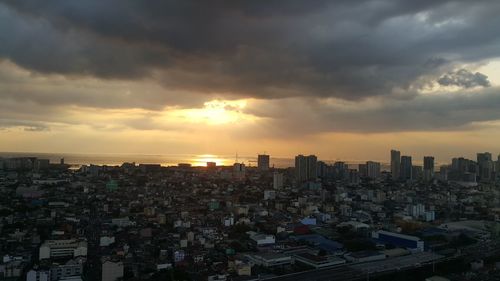 Cityscape against cloudy sky at sunset