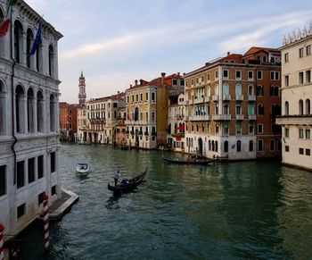 Canal amidst buildings in city against sky