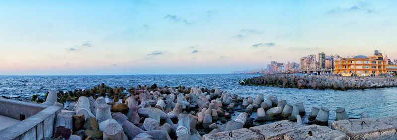 Panoramic shot of tetrapods by sea against sky during sunset