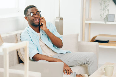 Young woman using mobile phone while sitting at home