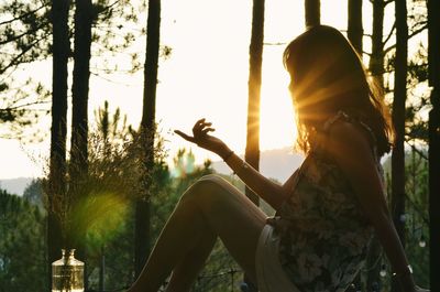 Side view of young woman sitting on tree trunk