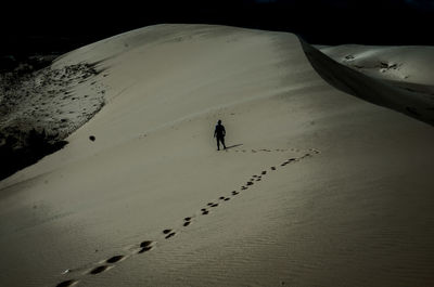 High angle view of footprints leading to person on desert