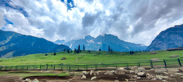 Panoramic view of field and mountains against sky