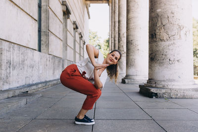 Portrait of young woman standing against brick wall doing yoga 