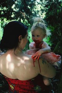 Mother holding daughter with blood on field