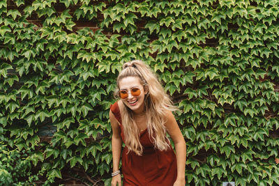 Portrait of smiling young woman standing against plants