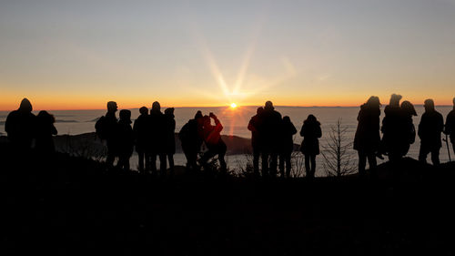 Silhouette people on beach against sky during sunset