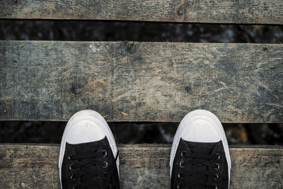 Directly above shot of canvas shoes on wooden footbridge