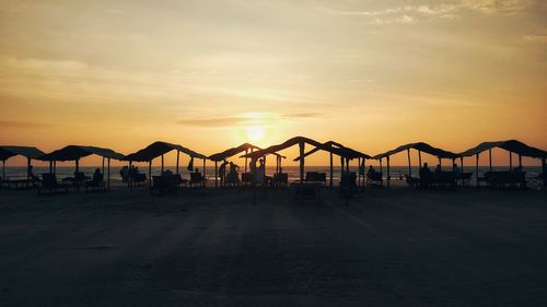 Silhouette people on beach against sky during sunset