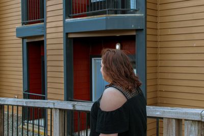 Rear view of woman standing outside house