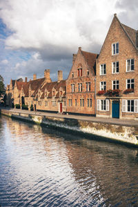 Buildings by canal against sky in city